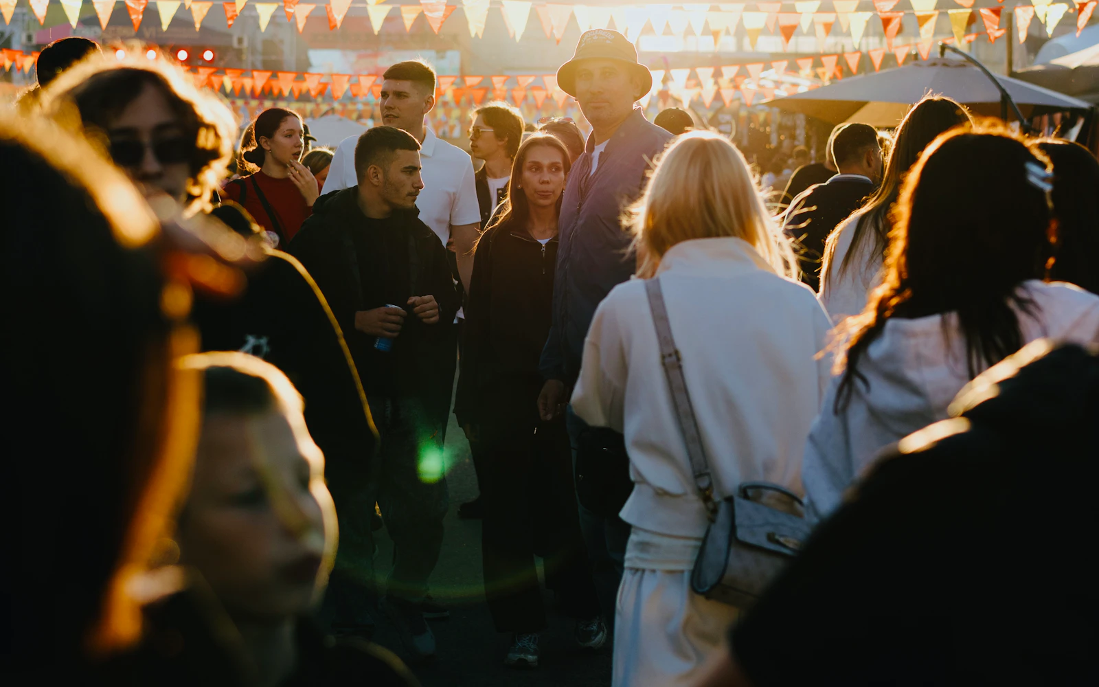 A crowd enjoying an outdoor community festival in low sunlight