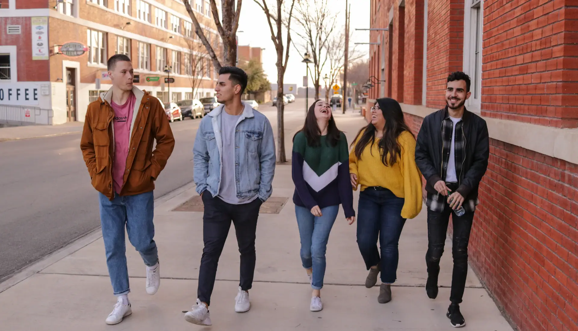 A mixed group of friends laughing while walking together in the city