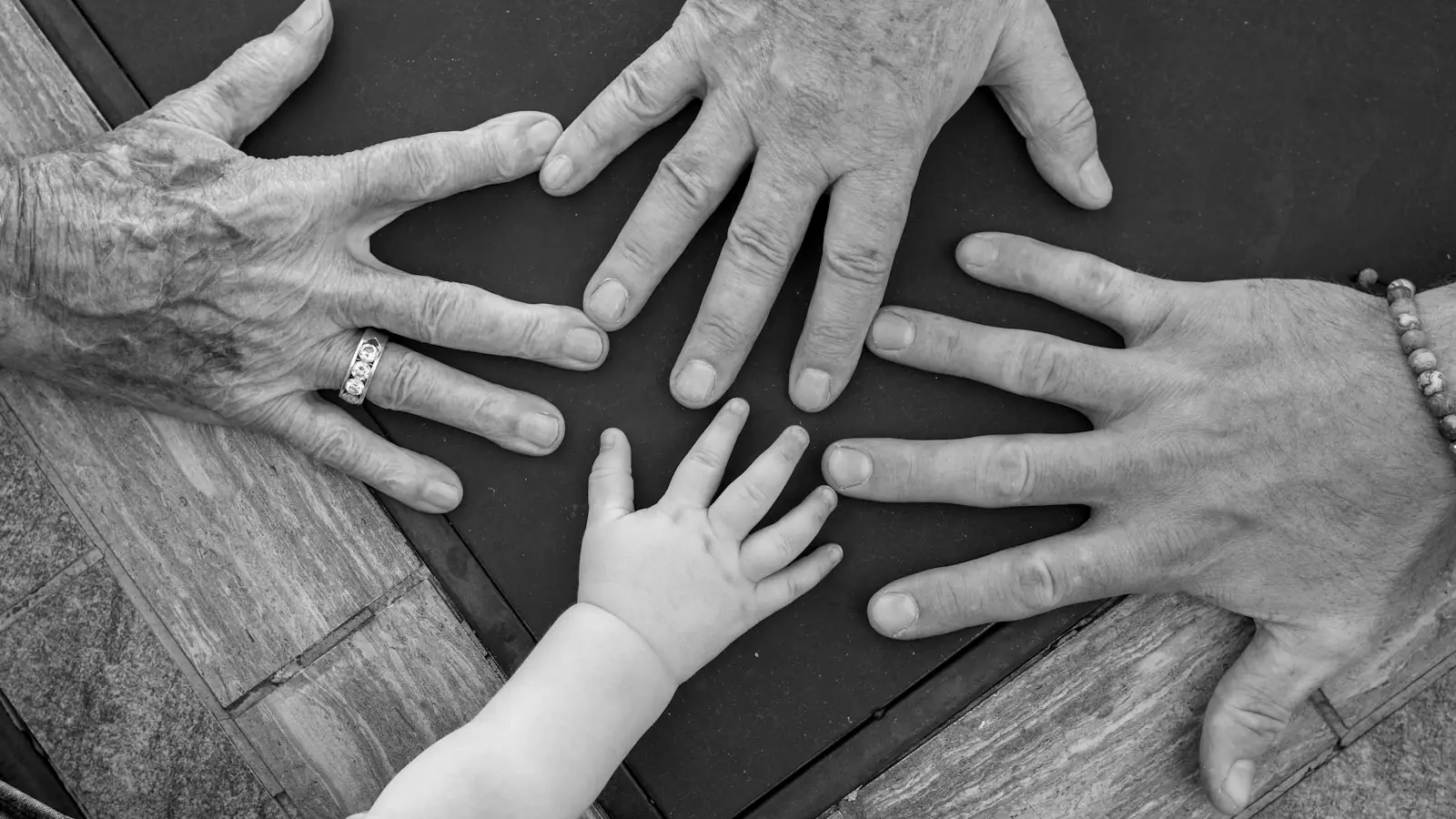 Hands of different generations reaching together at the centre of a group