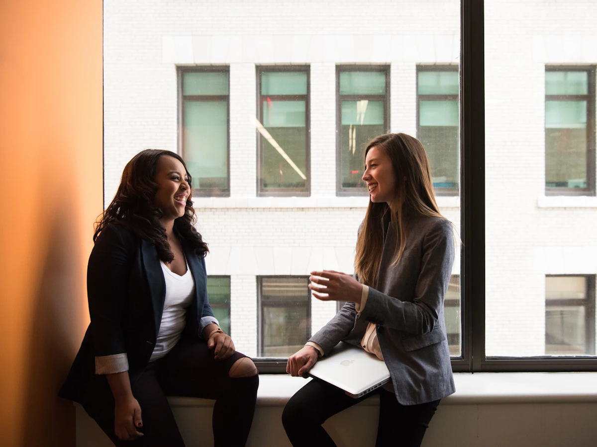 A professional laughing with a client during a one-to-one conversation by a window